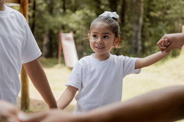 Little girl playing in the park hand in hand with her family - family making a circle - concept of unity and solidarity