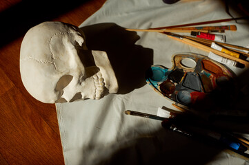 Plaster skull in the artist's studio along with paints and brushes.