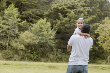 Hispanic dad hugging his little daughter in the park-father and daughter outdoors