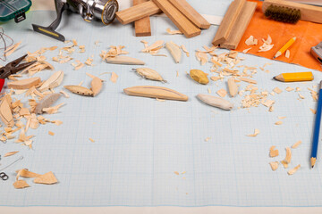 Handmade wooden fishing tacles graph paper background with tools and blanks.