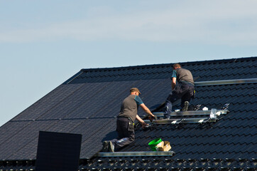Installing modern black solar panels on the roof