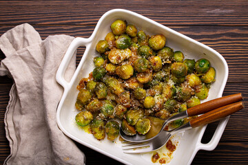Healthy vegetarian dish roasted brussels sprouts with butter and parmesan cheese in white ceramic...
