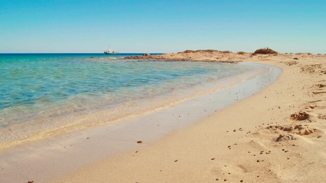 Golden Sand zna Ship on Turquoise Water. Mediterranean Sea Beach on Chrisi Island in Greece, Europe. Summer Holiday B-roll or Background with Copy Space. 4K Hand held B-roll Shot. Wide Low Angle View