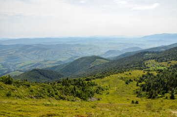 A view from the mountain ridge down to the meadow and forest hills. Carpathian mountains, Ukraine. Silence and harmony of nature.