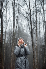 Girl in a raincoat on the background of the forest in the snow