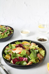 Italian shrimp salad with oranges, red onions, green lettuce, olive oil and sesame seeds. Green mix salad with shrimps, oranges, olive oil and sesame seeds, vertical photo copy space