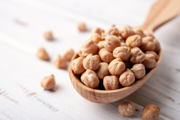Raw chickpea beans in wooden spoon bowl on kitchen table. Uncooked chickpeas
