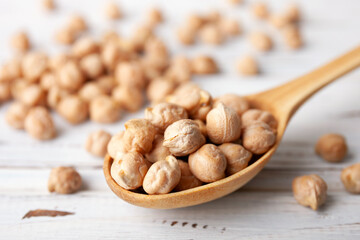 Raw chickpea beans in wooden spoon bowl on kitchen table. Uncooked chickpeas