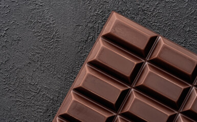 Close-up of broken pieces of chocolate on a dark stone background.