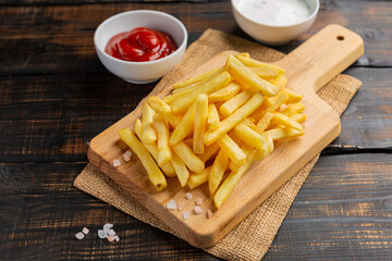 French fries served on cutting board on wooden table