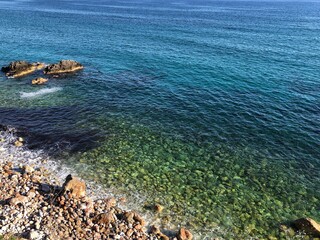 Top view of the beautiful waves of the mediterranean sea breaking on the coast of the rocky coast