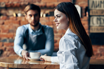 happy woman with cup of coffee and man bartender in apron