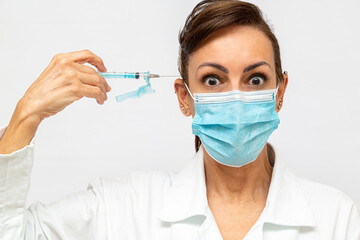 medica com com olhos arregalados com cara de assustada, segurando uma seringa com agulha e apontada...