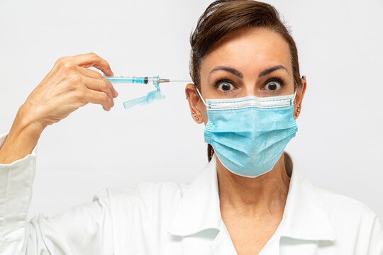medica com com olhos arregalados com cara de assustada, segurando uma seringa com agulha e apontada para sua cabe&ccedil;a