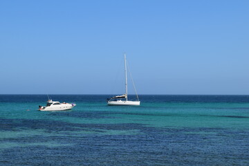 relaxing on a yacht in the ocean, torquoise water with boats, blue sky and horizon with sailboats, nautical vacations, luxury leisure lifestyle, outdoor water tourism with catamarans