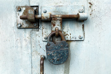 Close up view of old weathered lock on the metal door - old abandoned garage doors with padlock. Selective focus