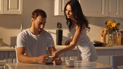 brunette woman serving cup of coffee to boyfriend