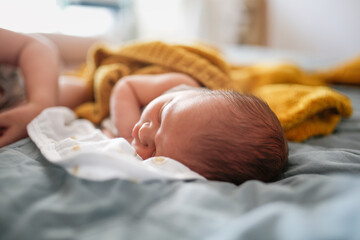 Newborn baby sleeping on a bed, top view, gray, blue and yellow color, cozy photo with a blanket