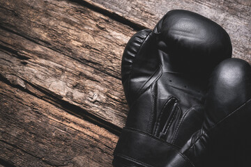 Old black boxing gloves on the wooden board background with copy space.
