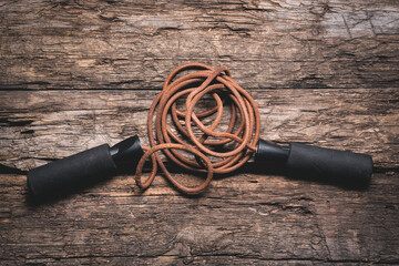 A brown skipping rope on the wooden floor flat lay background.