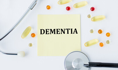 On white background a stethoscope, pills and with yellow card with text DEMENTIA
