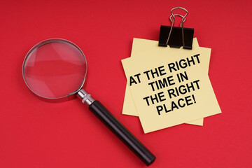 On a red background, a magnifying glass and a sticker with the inscription - At the right time in the right place
