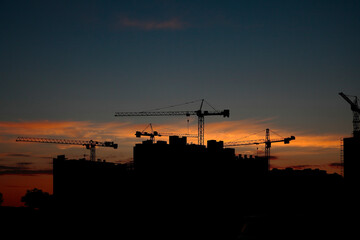 Construction cranes on the background of the sunset