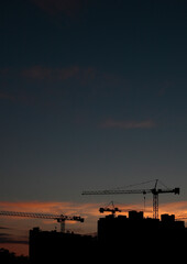 Construction cranes on the background of the sunset