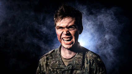 Portrait of a soldier in scars and battle paint, which screams on a black background with illuminated blue smoke