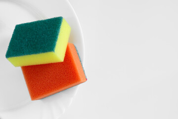 Yellow and orange dish sponge on white plate and light background