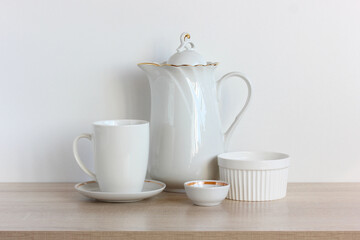group of white dishes on the table. coffee pot and mug.