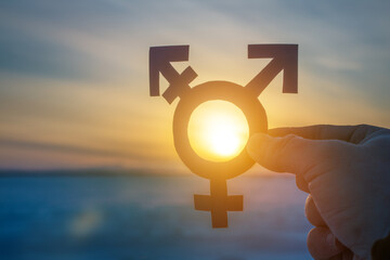 Transgender symbol in the hand of a man against the backdrop of the sunset. lgbt, minority sex,...