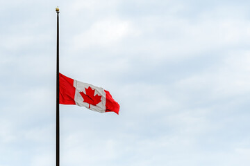 A Canadian flag at half mast, lowered in remembrance of the indigenous children who were abused and...