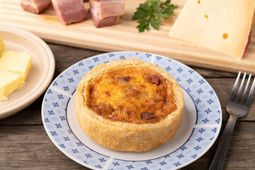 Homemade quiche lorraine over wooden board with ingredients