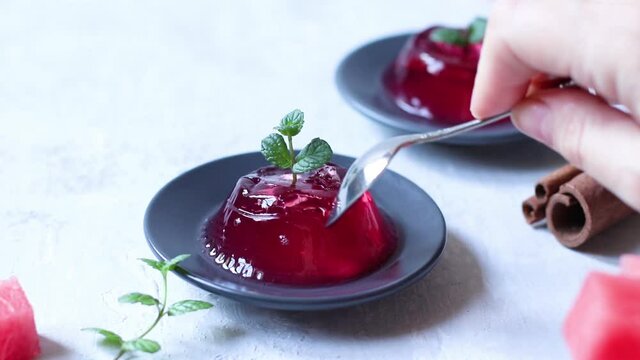 Two servings of jelly with mint and cinnamon on dark plates on a light background. Homemade watermelon dessert for breakfast. Copy space.