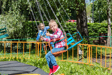 Everyday life of a disabled child. A boy with Down syndrome rides a chain carousel. A child on the...