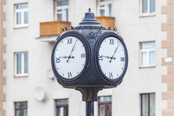Fototapeta na wymiar Retro style clock on the column on the street.