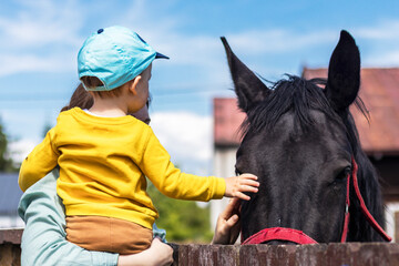 Dziecko z matką głaszczące konia.