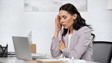 allergic businesswoman having headache near laptop on desk