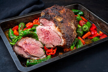 Traditional English barbecue lamb roast with vegetable and gravy sauce offered as close-up in a rustic metal tray