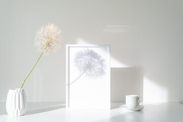 Empty white picture frame mockup in sunlight. Long shadow effect of shower head in the frame. Books...