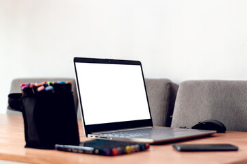 image of a computer with a blank screen on a wooden desk with a cell phone and crayons of various colors around it.