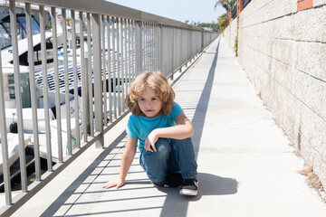 Boy child take short break hunkering down on promenade, rest