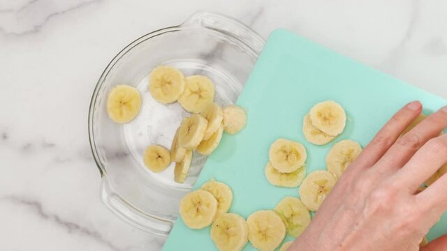 Banana slices close up on a glass plate, flat lay, woman hands