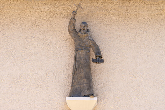 Santa Inez, CA, USA - May 26, 2021:San Lorenzo Seminary. Closeup of gray preaching monk statue on beige wall above main entrande door to the church