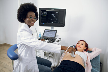 Ultrasound concept, obstetrics. Horizontal image of pleasant young afro-american female doctor,...