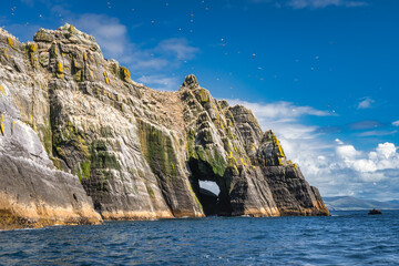 Natural arch or cave in Little Skellig island with hundreds of Gannets, Morus Bassanus flying...