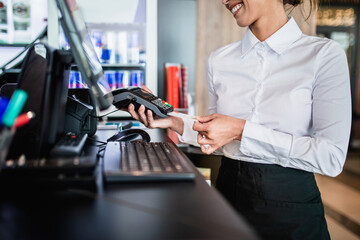 Female bartender holding a credit card reader machine and a payment card to charge the customer...