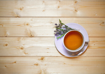 A cup of fragrant herbal tea with thyme. On a wooden countertop.