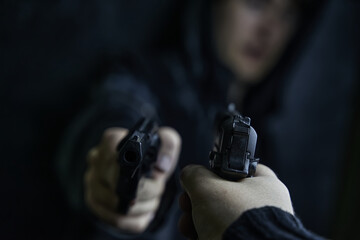 Two shooters threaten each other with weapons. First-person view of hand with pistol pointed at guy...